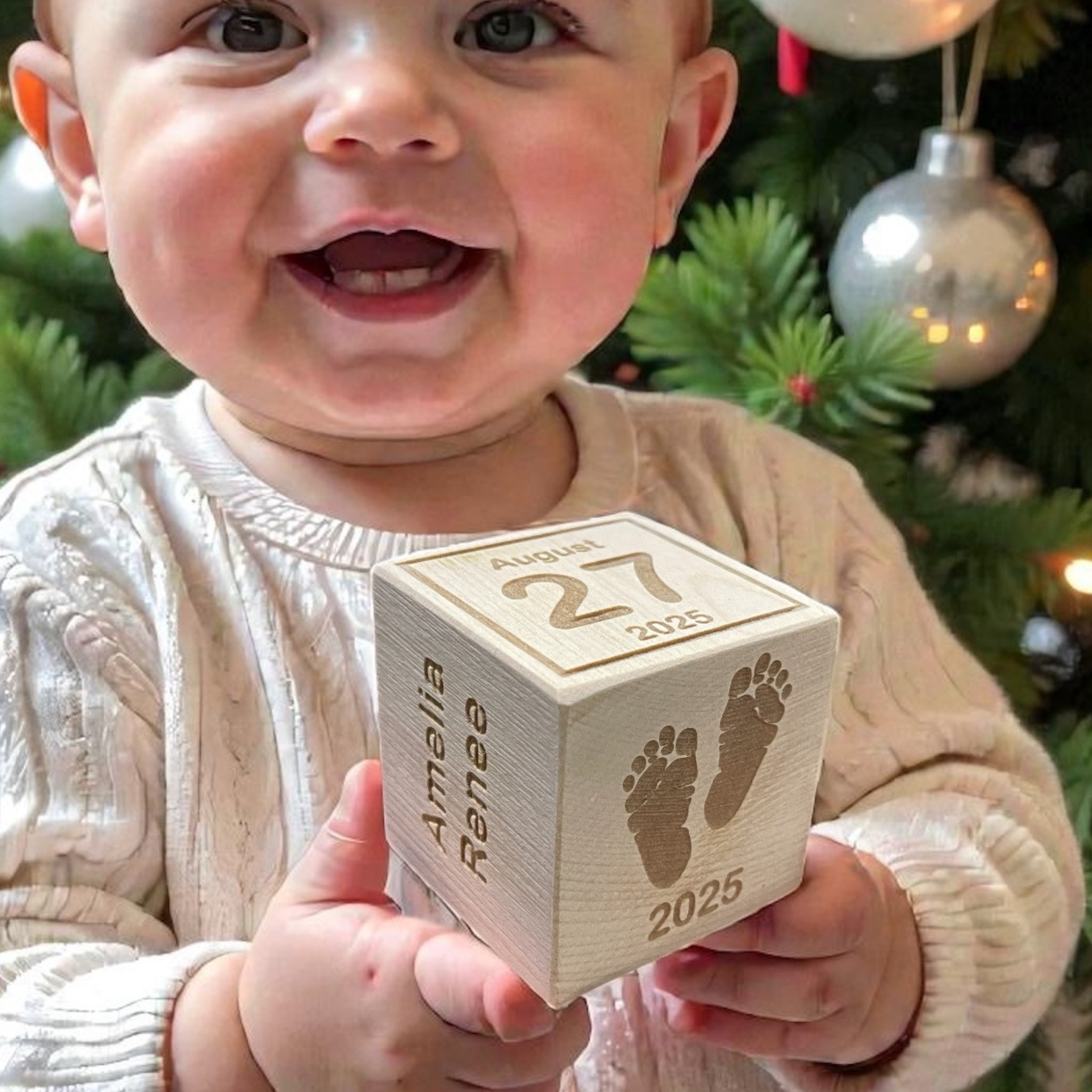 Smiling baby playing with personalized wooden Christmas block ornament