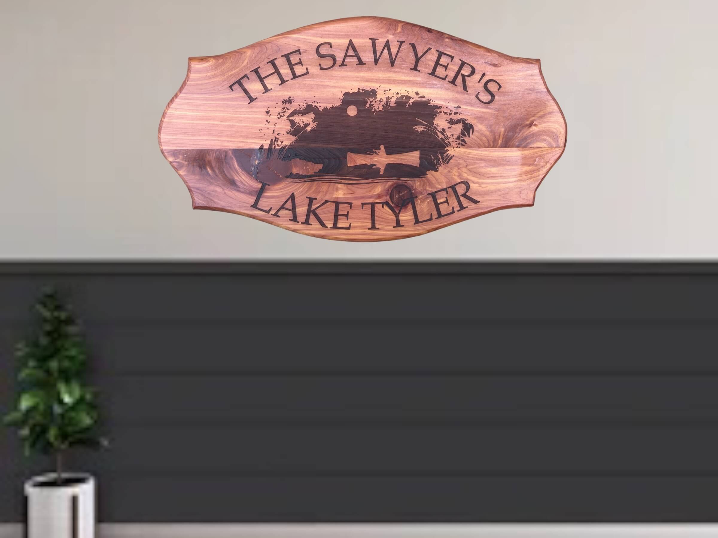 Personalized Cedar Lake House Wall Art" Description: A personalized wall art piece for your lake house, crafted from cedar wood. The center of the sign displays a laser-engraved image of a man fishing in a small boat.