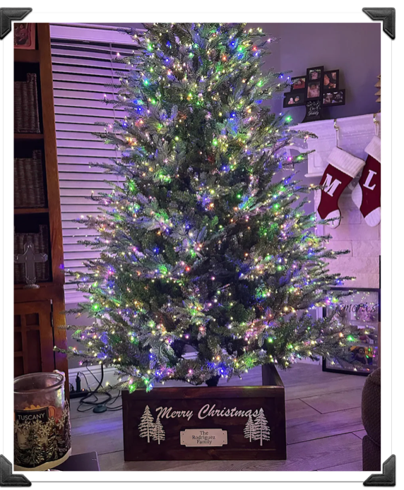 Fully decorated Christmas tree displayed on top of a wooden farmhouse-style Christmas tree collar with X-trim.