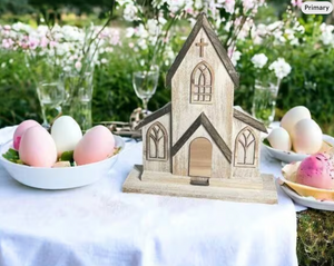 Wooden church model on a table with Easter eggs and flowers