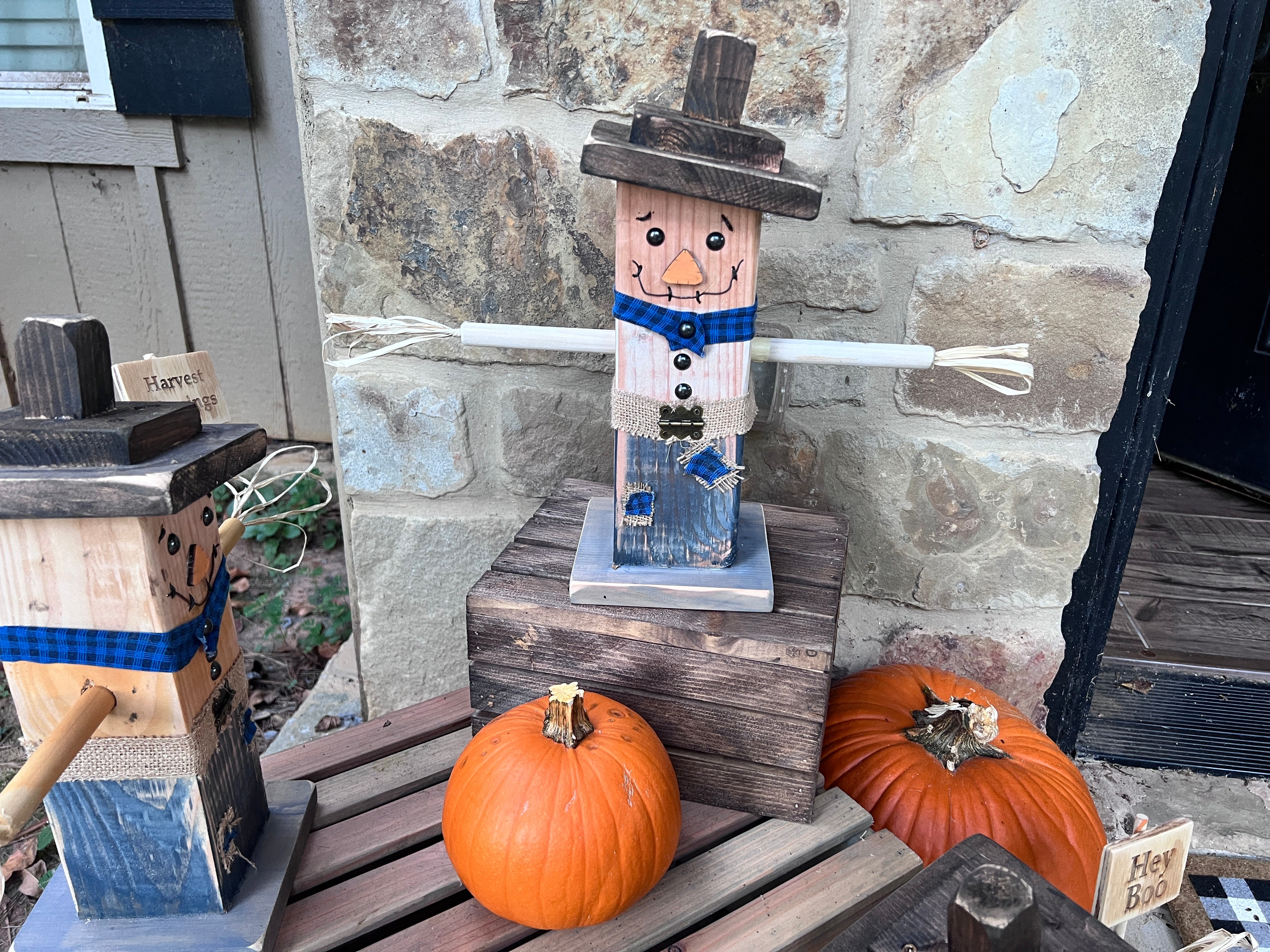 Rustic wooden scarecrow set up in an entryway with pumpkins and hay bales for a cozy farmhouse autumn display