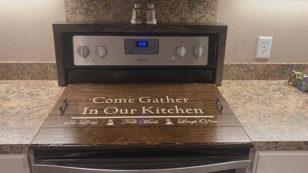 Beautiful Stove Top Cover stained in Espresso color with the words " Come Gather In our Kitchen" painted on it in an off-white/cream color. Also has the words sit long, talk much, and laugh often painted on it. 