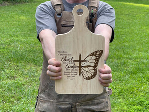 A picture of the Scripture Charcuterie board showing it being held by the maker.See more at SawyerCustomCrafts.com