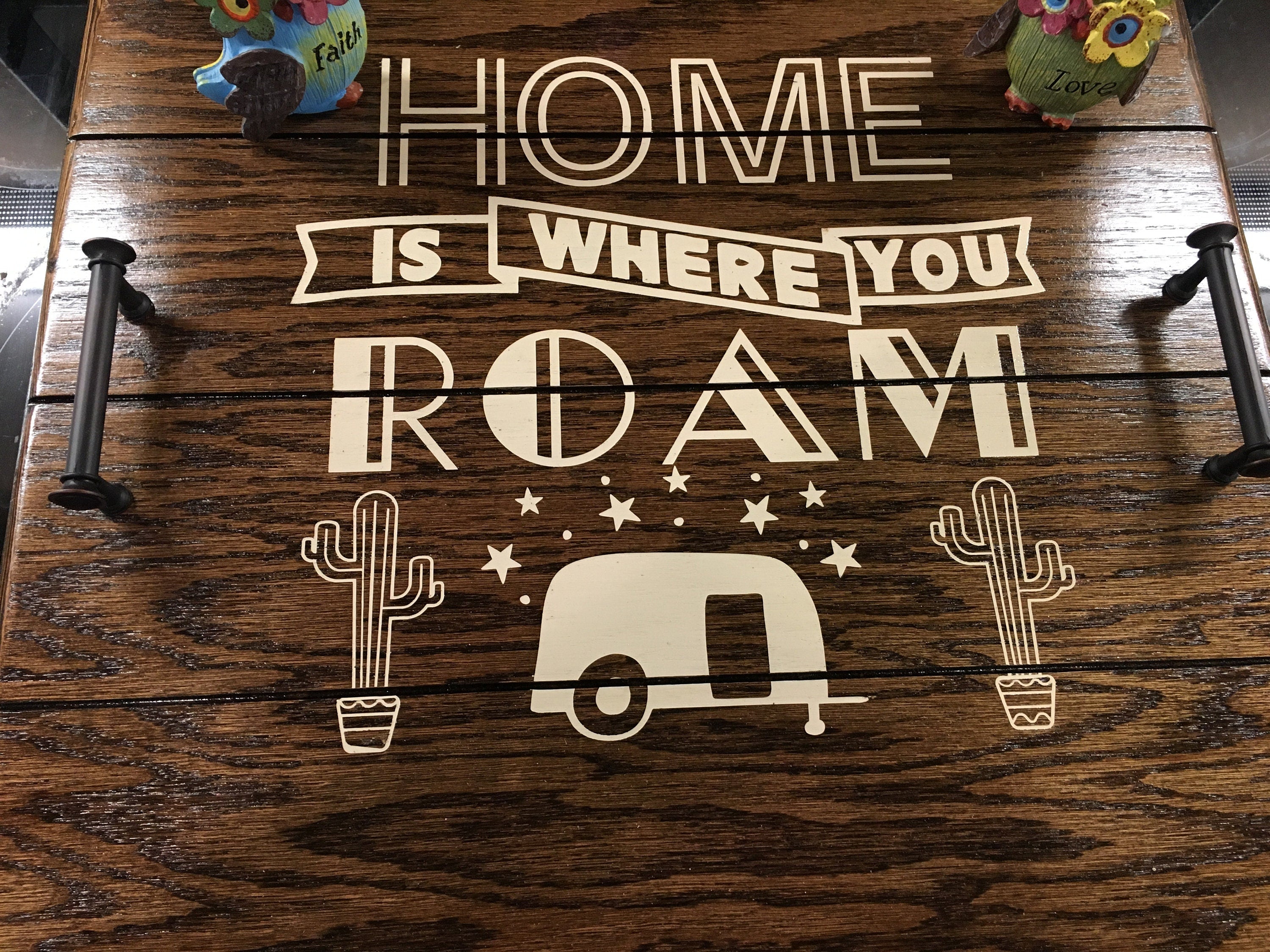 Top View of Picture of RV sized Stove Top Cover. This Cover is stained in Espresso Stain with the words "Home is where you Roam" painted on in cream colored paint. Also has a small picture of an RV With a picture of a cactus on either side of it. Find more info at SawyerCustomCrafts.com